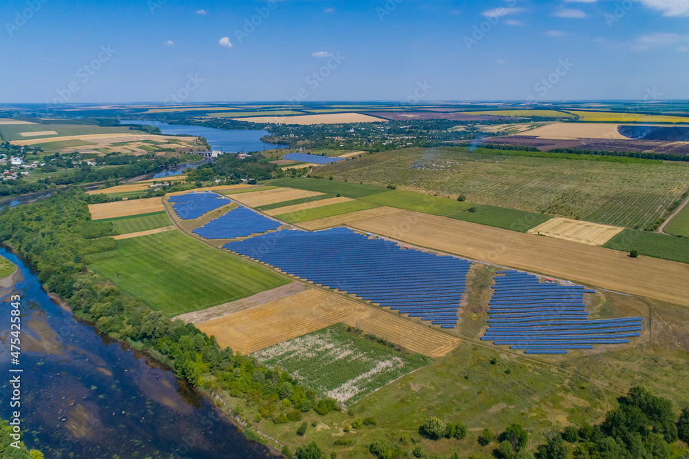 Solar power plant, solar panels shot from a drone, blue sky and clouds