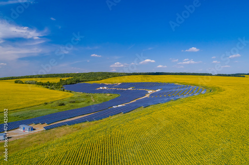 Solar power plant, solar panels shot from a drone, blue sky and clouds