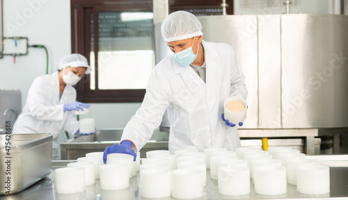 Fotografie Confident man in white coat and protective face mask engaged in cheesemaking sha