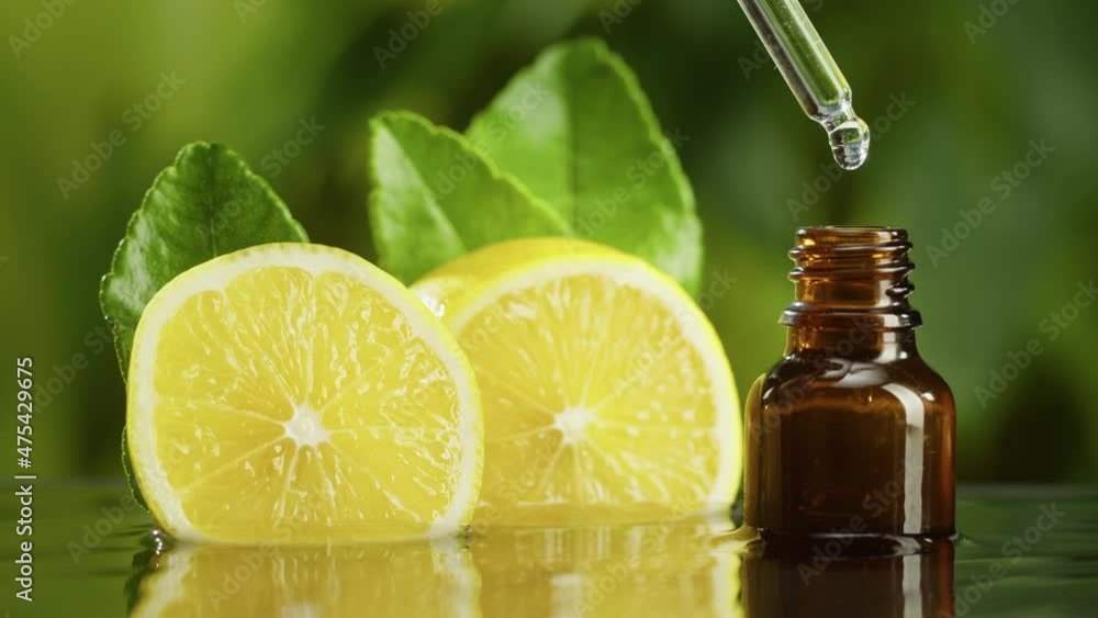 Dripping lemon juice from pipette into bottle close-up, vitamin oil. Making aroma serum on green background. Dropping liquid citrus extract, skincare routine, treatment spa. Traditional medicine. Dripping lemon juice from pipette into bottle close-up, vitamin oil. Making aroma serum on green background. Dropping liquid citrus extract, skincare routine, treatment spa. Traditional medicine.