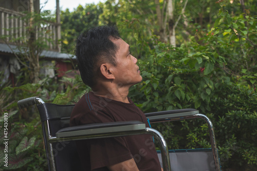 A paraplegic middle aged man in his wheelchair stares blankly while outside his home. A bored and lonely person. photo