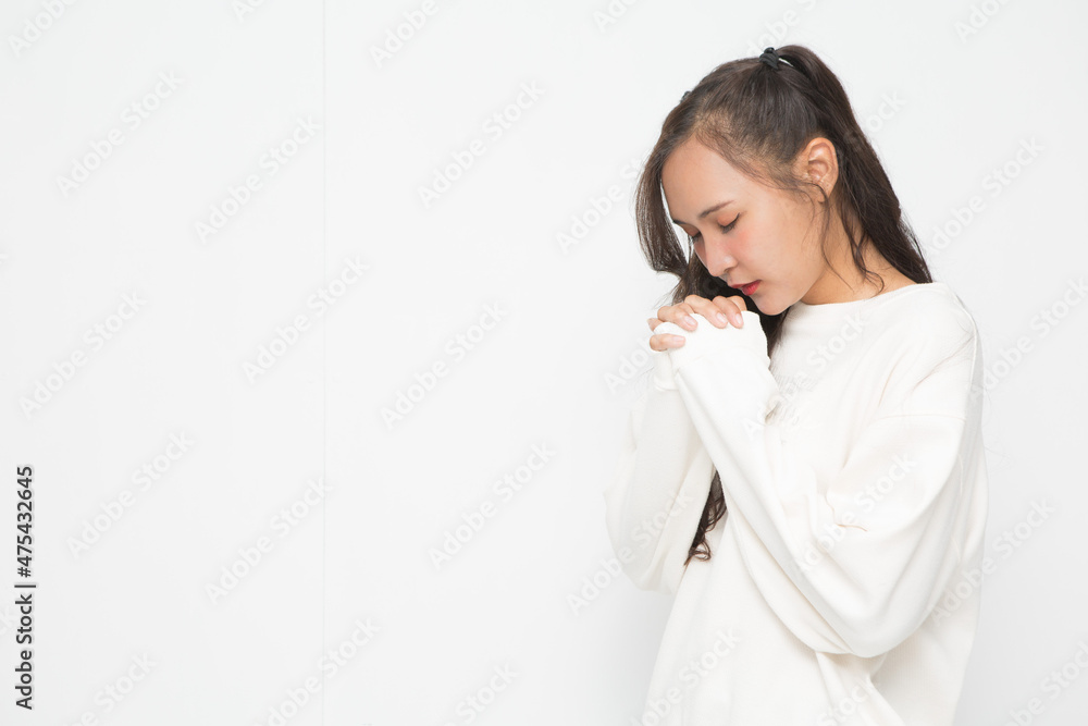 Beautiful Asian woman wearing white sweater praying on white background. Beautiful Asian woman wearing white sweater praying on white background.