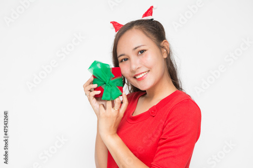 Beautiful Asian woman wearing small Santa hat and wearing red dress holding red gift box on white background.