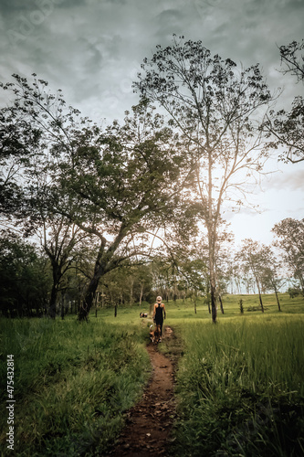 A woman walking with the dogs at Kalibendo plantation Indonesia.