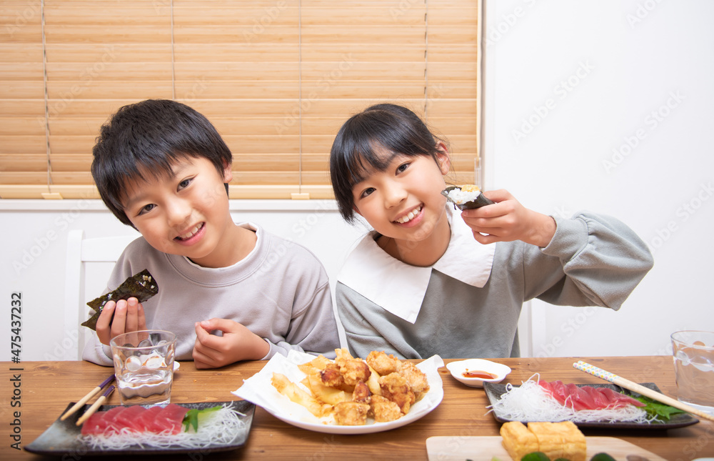 家で晩御飯を食べる小学生の男の子と女の子