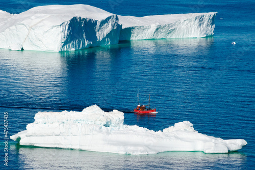 Boat approaching Icebergs of Sermermiut, Ilulissat, Greenland photo