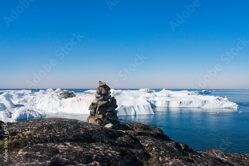 Cairn (pile of stones) overlooking icebergs of Sermermiut, Ilulissat, Greenland