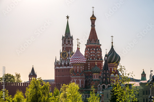 Multi-colored domes of St. Basil's Cathedral and the Spasskaya Tower of the Moscow Kremlin around the trees. Symbols of the Russian state.