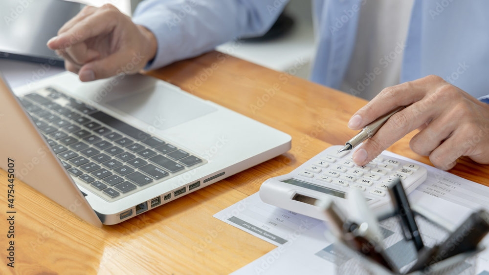 Financial or accounting professionals use a laptop to analyze the company's revenue-expenses graph to prepare for presentation to the chief executive and partner, Calculate data with a calculator. Financial or accounting professionals use a laptop to analyze the company's revenue-expenses graph to prepare for presentation to the chief executive and partner, Calculate data with a calculator.