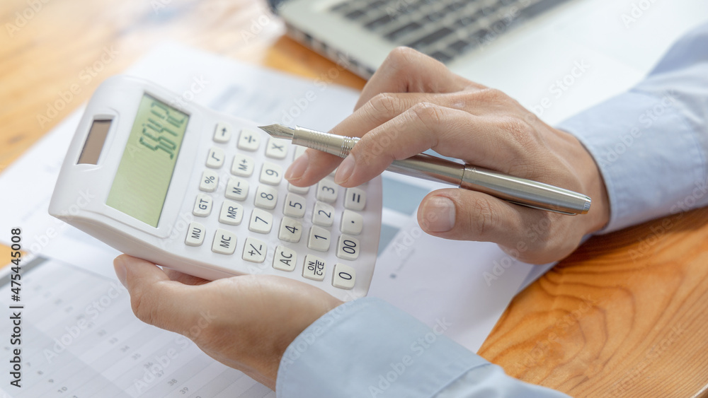 Businessman presses a calculator to calculate earnings and analyze company earnings in his private office, Information in finance and accounting, Company performance and revenue. Businessman presses a calculator to calculate earnings and analyze company earnings in his private office, Information in finance and accounting, Company performance and revenue.