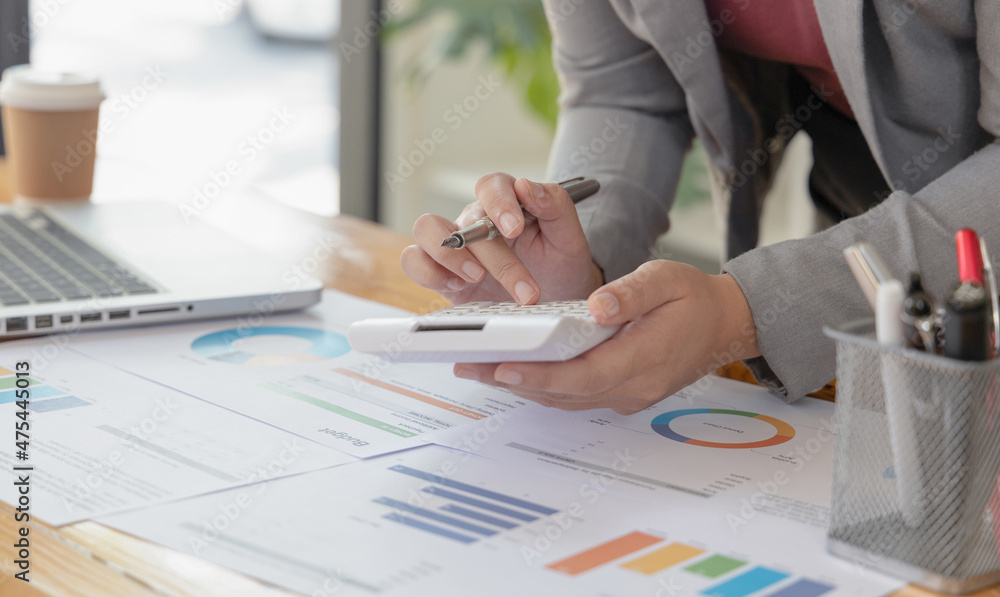 Young Asian businesswoman presses a calculator to calculate income tax and corporate income in a private office, Finance, Accounting, Tex, Statistical graphs of marketers investing in real estate. Young Asian businesswoman presses a calculator to calculate income tax and corporate income in a private office, Finance, Accounting, Tex, Statistical graphs of marketers investing in real estate.