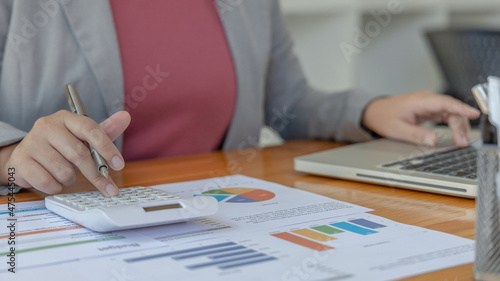 Young Asian businesswoman presses a calculator to calculate income tax and corporate income in a private office, Finance, Accounting, Tex, Statistical graphs of marketers investing in real estate.