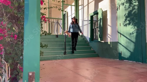 Sightseeing female wearing hat walking down green steps of Rancho Camulos museum California photo