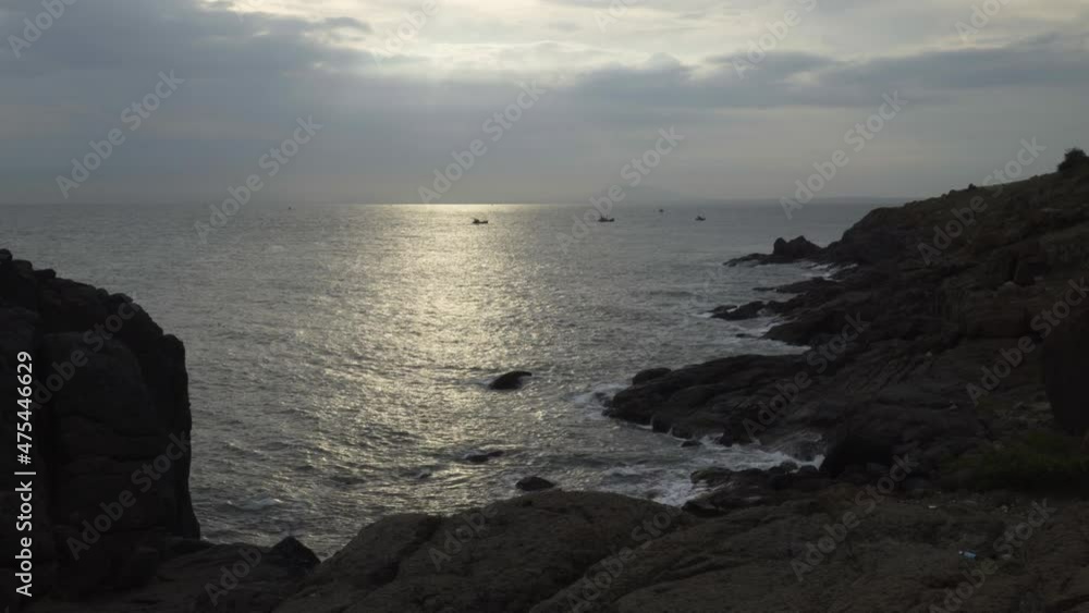 Beautiful sunset view from a rocky beach at Muine peninsula,Vietnam with small boat at a distance. Beautiful sunset view from a rocky beach at Muine peninsula,Vietnam with small boat at a distance.