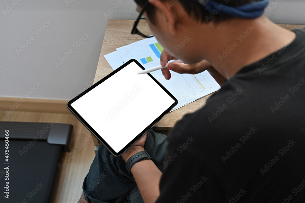 Rear view young start up businessman working with digital tablet at home office. Rear view young start up businessman working with digital tablet at home office.