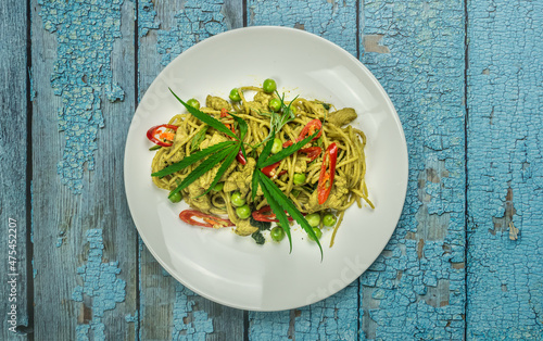 Cannabis spaghetti with chicken green curry sauce  (Thai  style spaghetti khiao waan gai). It sits on the floor of an old blue wooden table. Copy space. Top view. photo