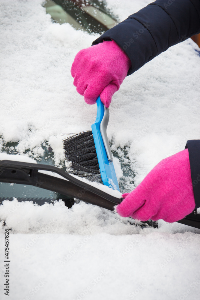 Hand of woman using brush and remove snow from car and windscreen Hand of woman using brush and remove snow from car and windscreen