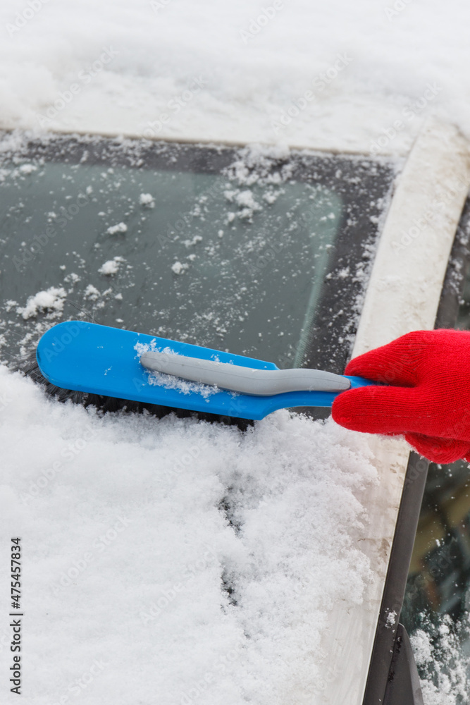 Hand using brush and remove snow from car and windscreen. Problems in winter Hand using brush and remove snow from car and windscreen. Problems in winter