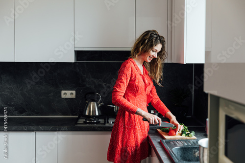 a woman housewife prepares a salad of fresh vegetables in the kitchen