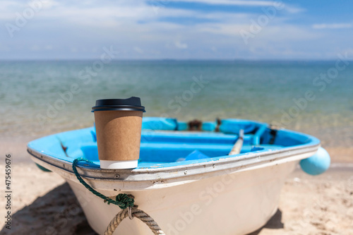 Paper coffee cup on the boat with sea background.