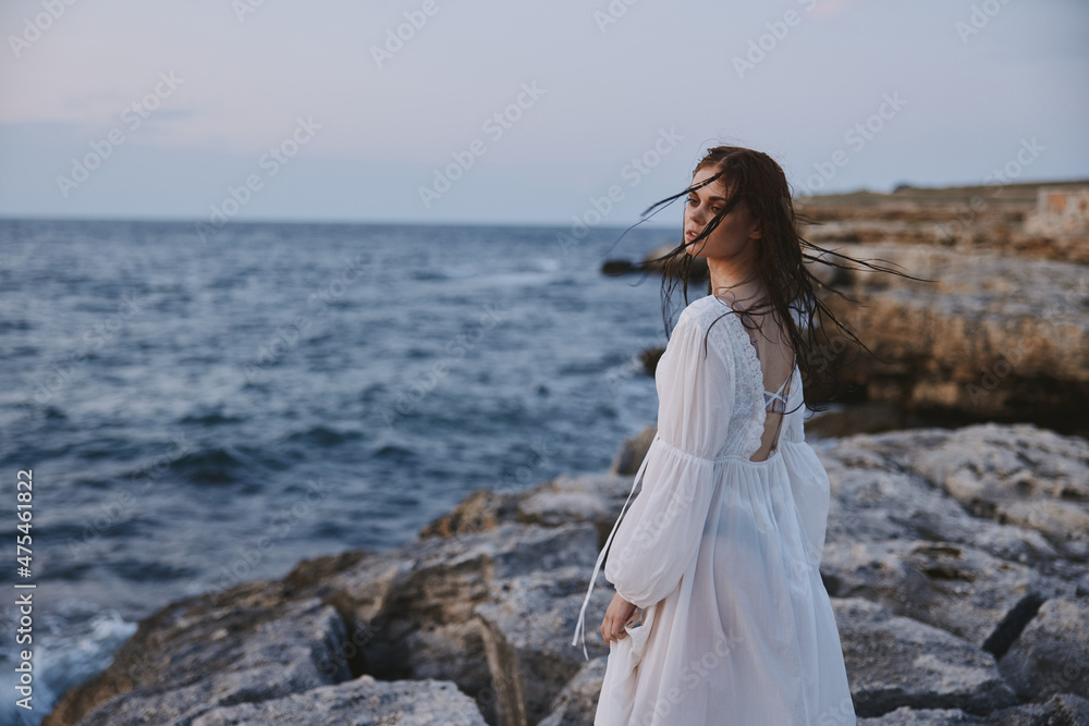 woman with wet hair in a dress on the stony shore of the ocean unaltered