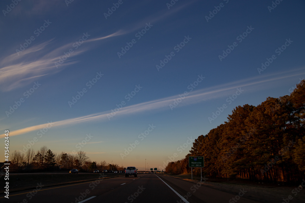Highway through forest and vast open field in America, spring