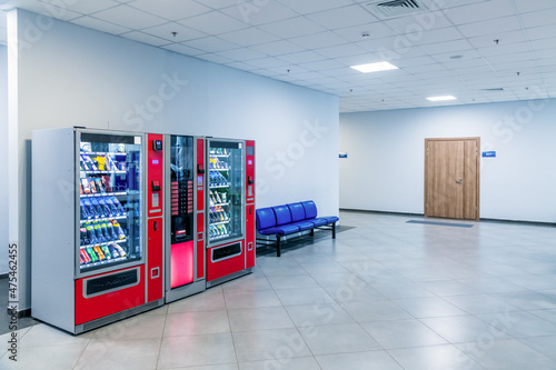 Group of red vending machines stands by the wall. Glare is reflected on a black screen. No people. Copy space for your text. Small business theme. photo