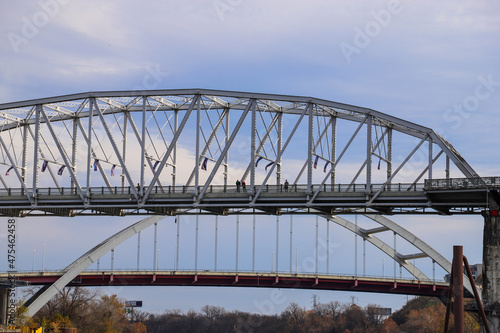 a shot of Cumberland river with the John Seigenthaler Pedestrian Bridge over the water surrounded by gorgeous autumn trees and grass with powerful clouds on the riverfront in Nashville Tennessee USA photo