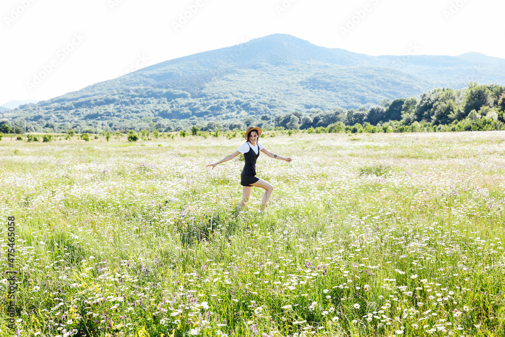 beautiful woman in a hat in a field of chamomile flowers