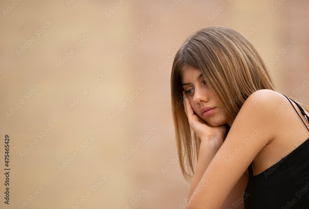 A young woman appears to be unhappy, looking downwards. A young woman appears to be unhappy, looking downwards.