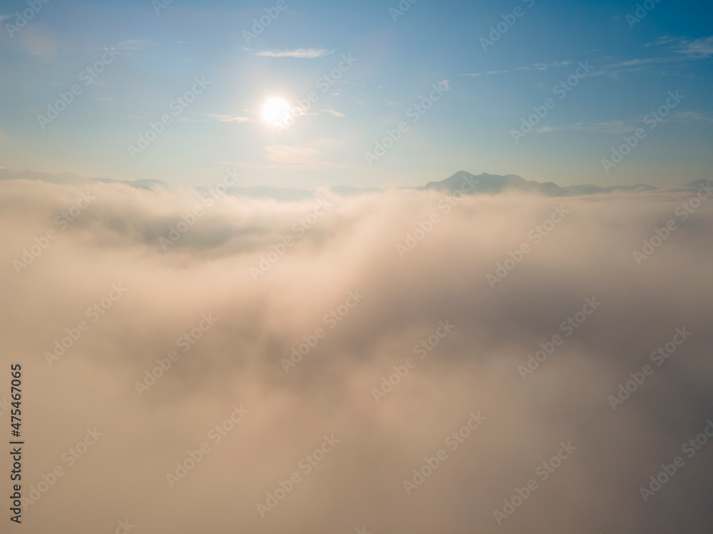 Sunrise over the amazing Sea of fog in the morning with blue sky. Aerial view with a drone among a sea of fog.