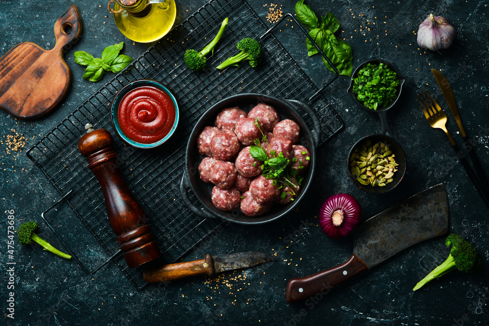 Fresh raw beef meatballs with spices in a pan. Top view. On a stone background.