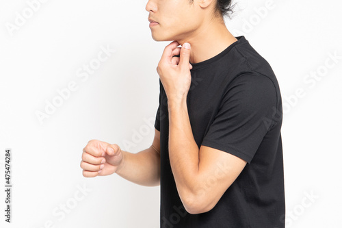 白い背景の前に立って喉が痛いポーズをする黒いTシャツを着ている男性 photo
