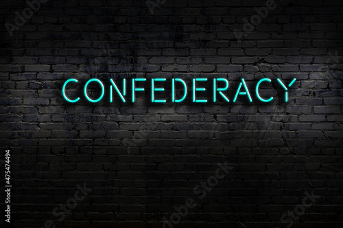 Neon sign. Word confederacy against brick wall. Night view