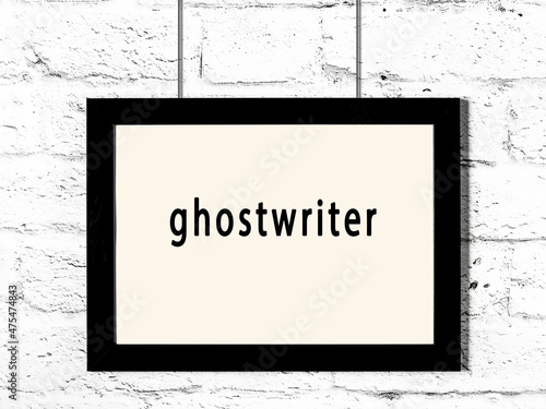 Black frame hanging on white brick wall with inscription ghostwriter