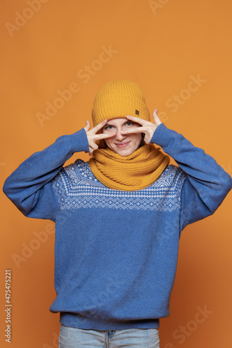 young red-haired girl in a warm hat and a knitted sweater on a yellow background © Екатерина Елисафенко