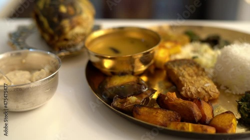 Close up shot of dish beautifully decorated over the silver bowl and cooper plate.An Bengali meal with rice vegetable and different type of dessert in a large plate at the occasion of baby shower. photo