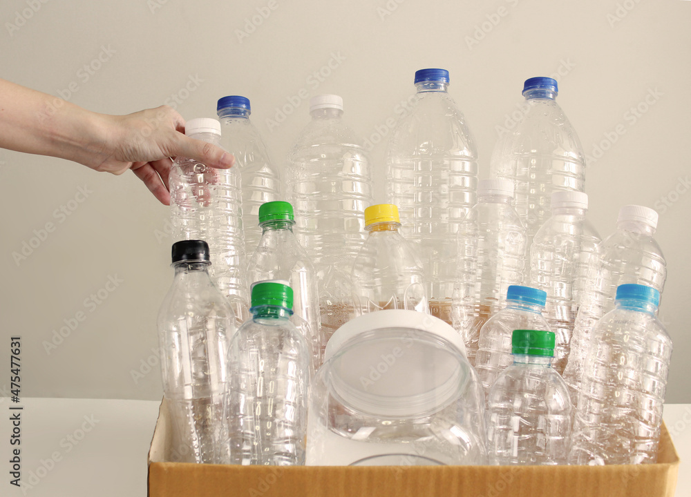 Woman's hand are put recycled plastic bottle into carton box in order to sorting process of trash for sustainability and environmental.A Save energy and World. Woman's hand are put recycled plastic bottle into carton box in order to sorting process of trash for sustainability and environmental.A Save energy and World.