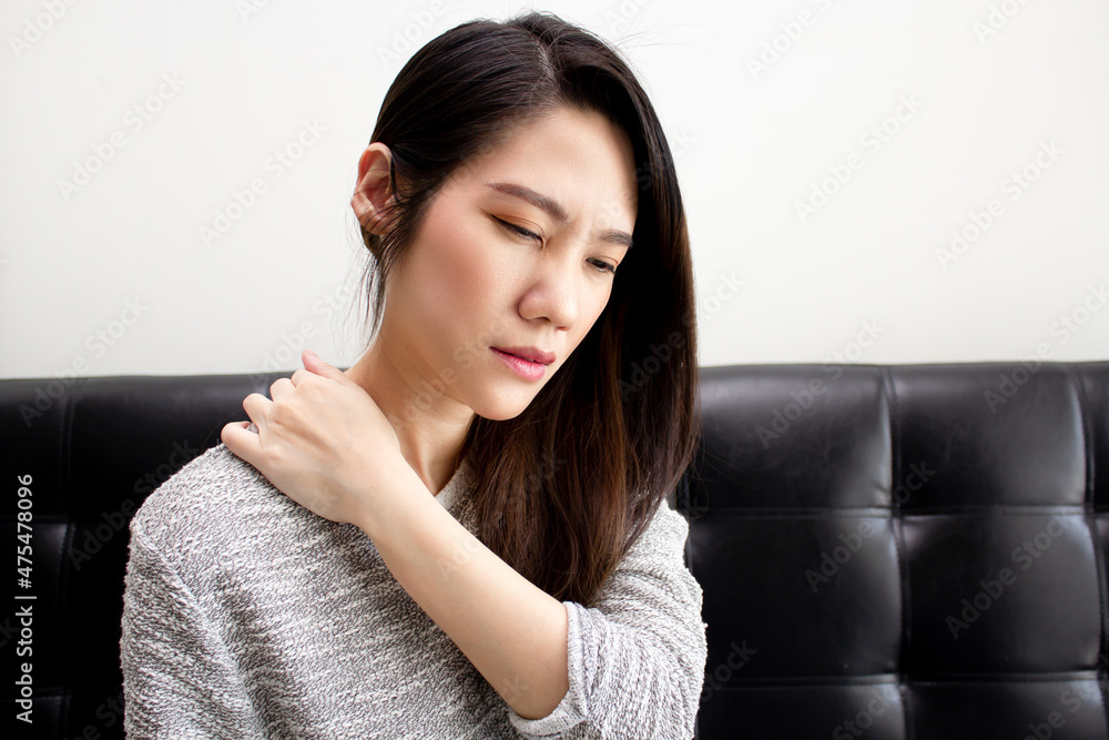 Asian woman who sitting in living room using hand touch her nape and feeling stress and pain caused by bad ergonomic and injure Asian woman who sitting in living room using hand touch her nape and feeling stress and pain caused by bad ergonomic and injure