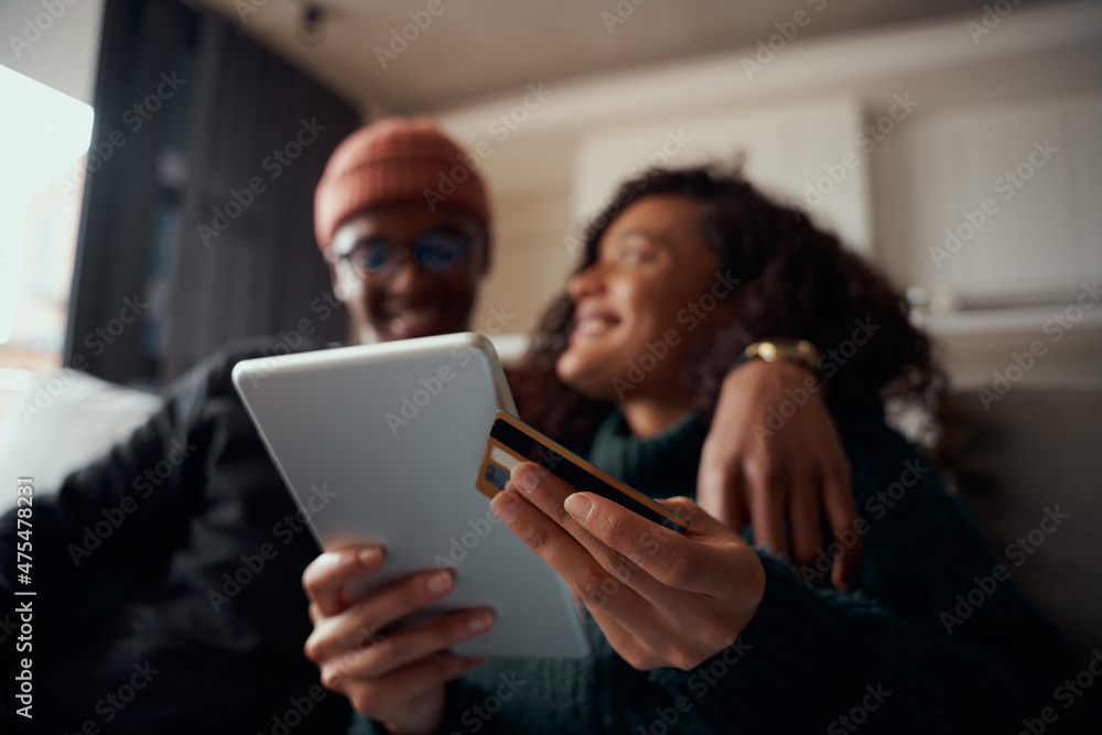 Online purchase being on tablet made by multi-ethnic couple on the sofa in the lounge Online purchase being on tablet made by multi-ethnic couple on the sofa in the lounge