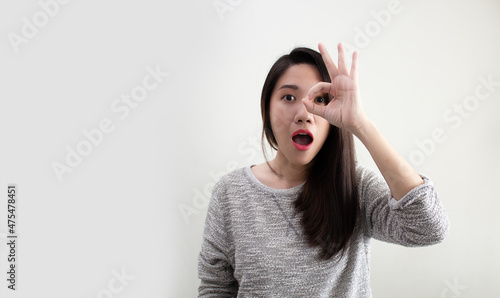Asian beautiful woman make agreement hand gesture in front of her eyes and mouth open with feeling surprise and unbelievable.