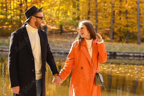 Young couple walking near water in autumn park