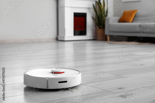 Modern robot vacuum cleaner on wooden floor in room