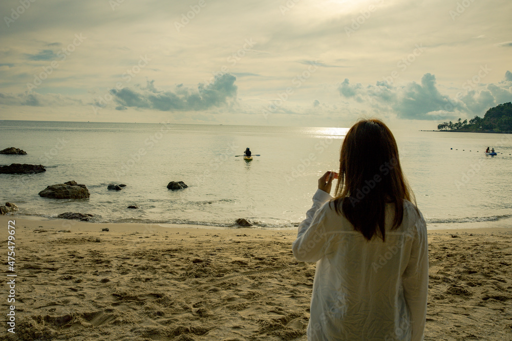 A beautiful Asian woman in a bikini walks amongst the beach rocks where the golden glow of the rising sun. A beautiful Asian woman in a bikini walks amongst the beach rocks where the golden glow of the rising sun.