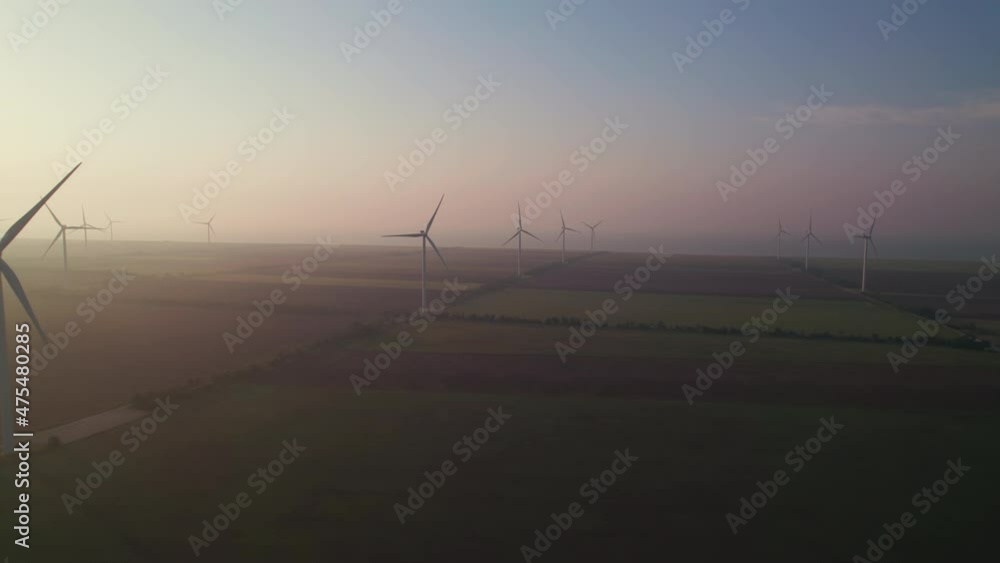 Windmills with rotating wings at sunrise or sunset or sunrise. Technology for wind energy, renewable energy source, earth care. Wind power station, drone video, moving toward the horizon, 4k Windmills with rotating wings at sunrise or sunset or sunrise. Technology for wind energy, renewable energy source, earth care. Wind power station, drone video, moving toward the horizon, 4k