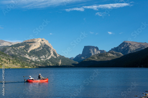 USA, Wyoming. Men relaxing on fishing raft, view of White Rock Mountain and Squaretop Peak above Green River Lake
