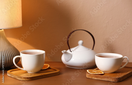 Cups of tasty tea and pot on table in cafe