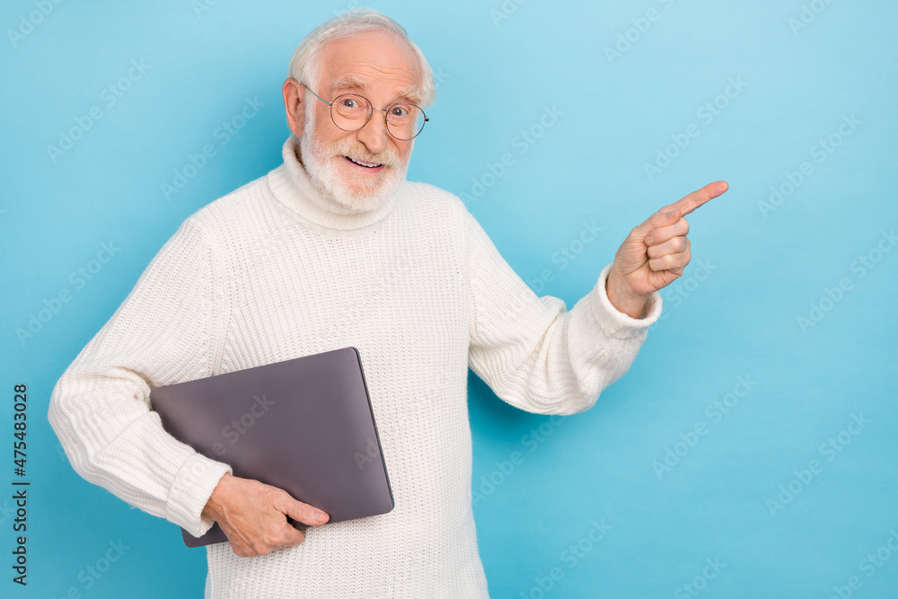 Portrait of attractive trendy cheery grey-haired man holding laptop showing copy space ad isolated over bright blue color background Portrait of attractive trendy cheery grey-haired man holding laptop showing copy space ad isolated over bright blue color background
