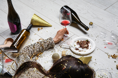 Sticker Drunk young woman with wine glass lying on floor after party