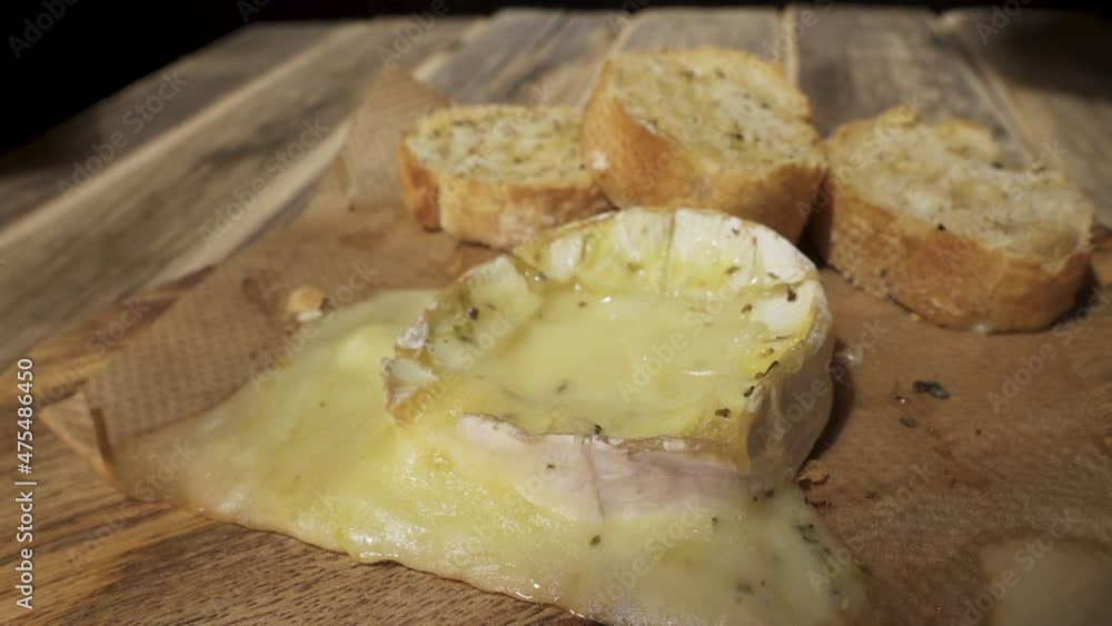 dipping a piece of baguette into baked melted Camembert cheese Stock